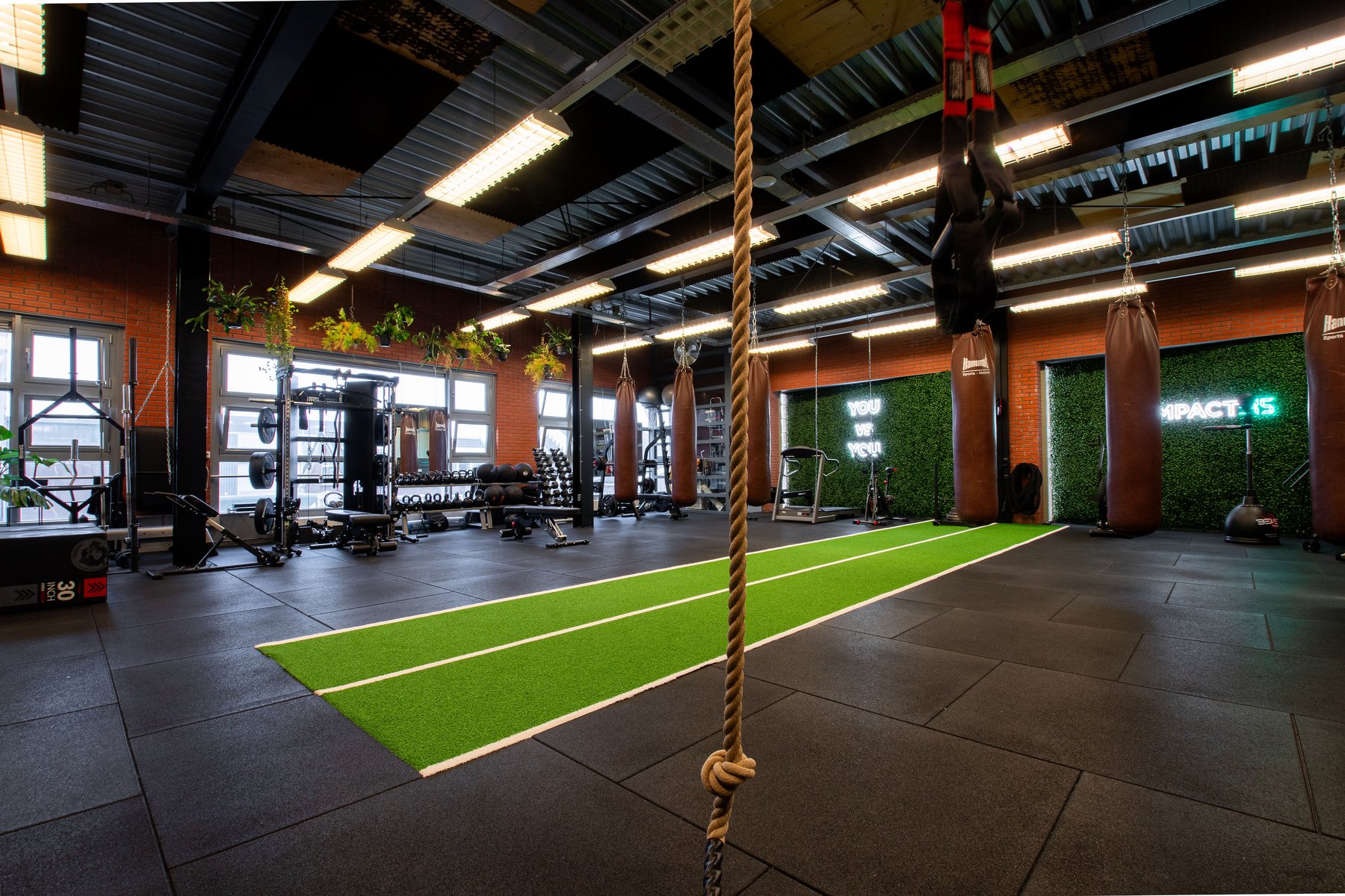 De trainingsvloer van Impact:45 in Woerden met kunstgras sprint-track, bokszakken en krachttoestellen
